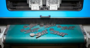 Stanzmaschine zum stanzen von Metallteilen -hier das Logo von SMT Metallverarbeitung Arnsberg